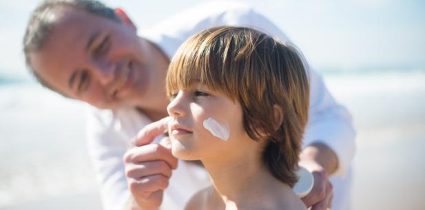 Vader smeert zonnebrand bij zoon