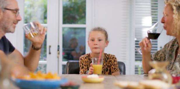 Jong meisje en moeder aan tafel met drinken