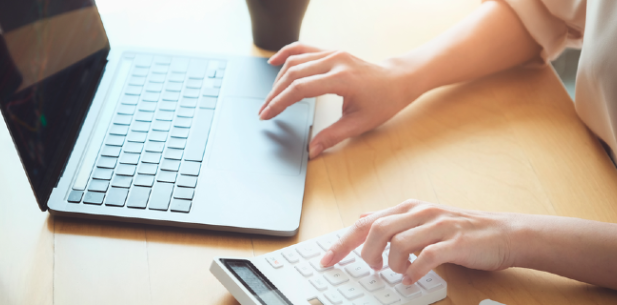 Vrouw werkt aan bureau op laptop en rekenmachine