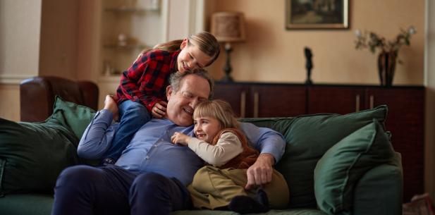Opa met kleindochters lachend op de bank