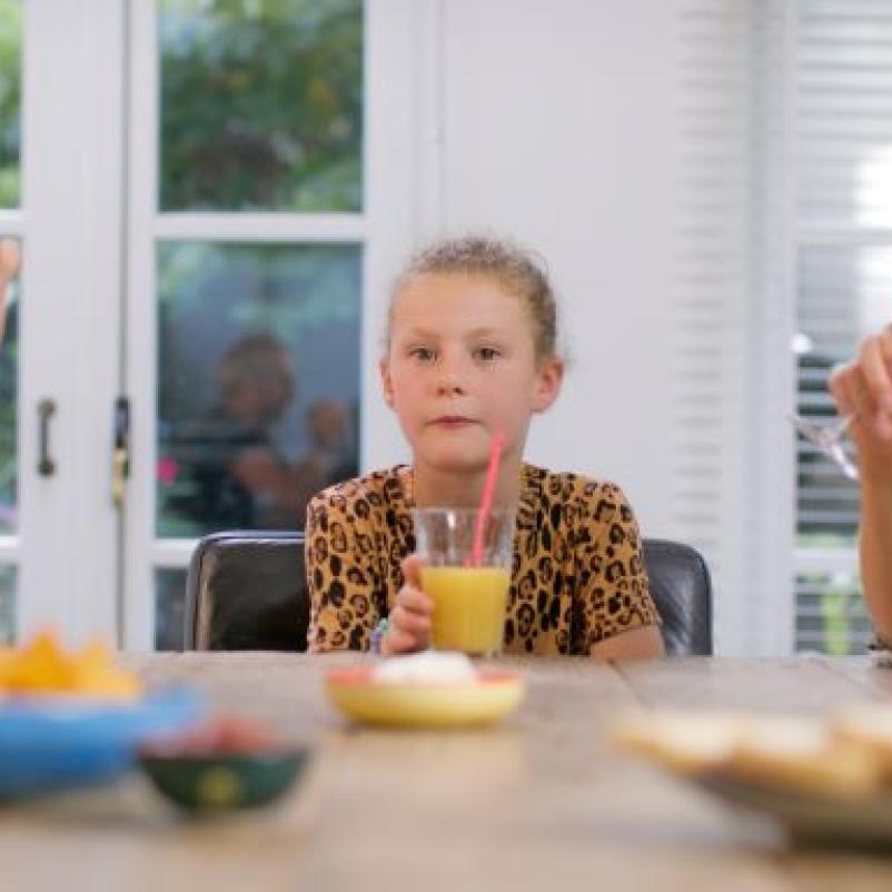 Jong meisje en moeder aan tafel met drinken