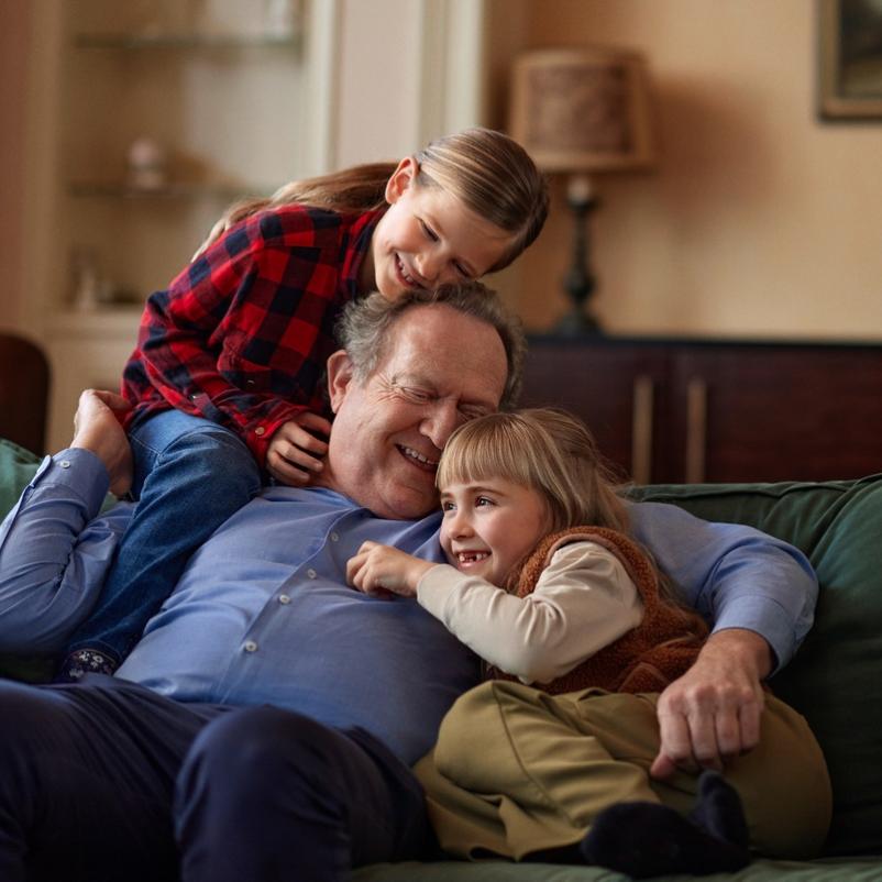 Opa met kleindochters lachend op de bank