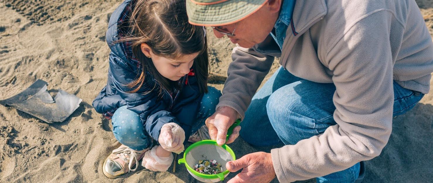 Opa en kleindochter op strand met zeef