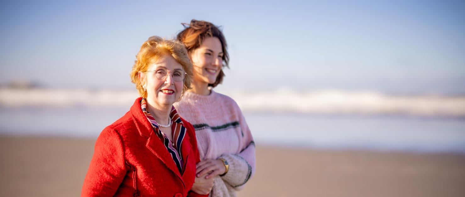 oudere vrouw loopt met dochter op het strand