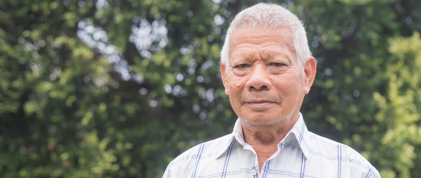 Portret oudere man met bomen in de achtergrond