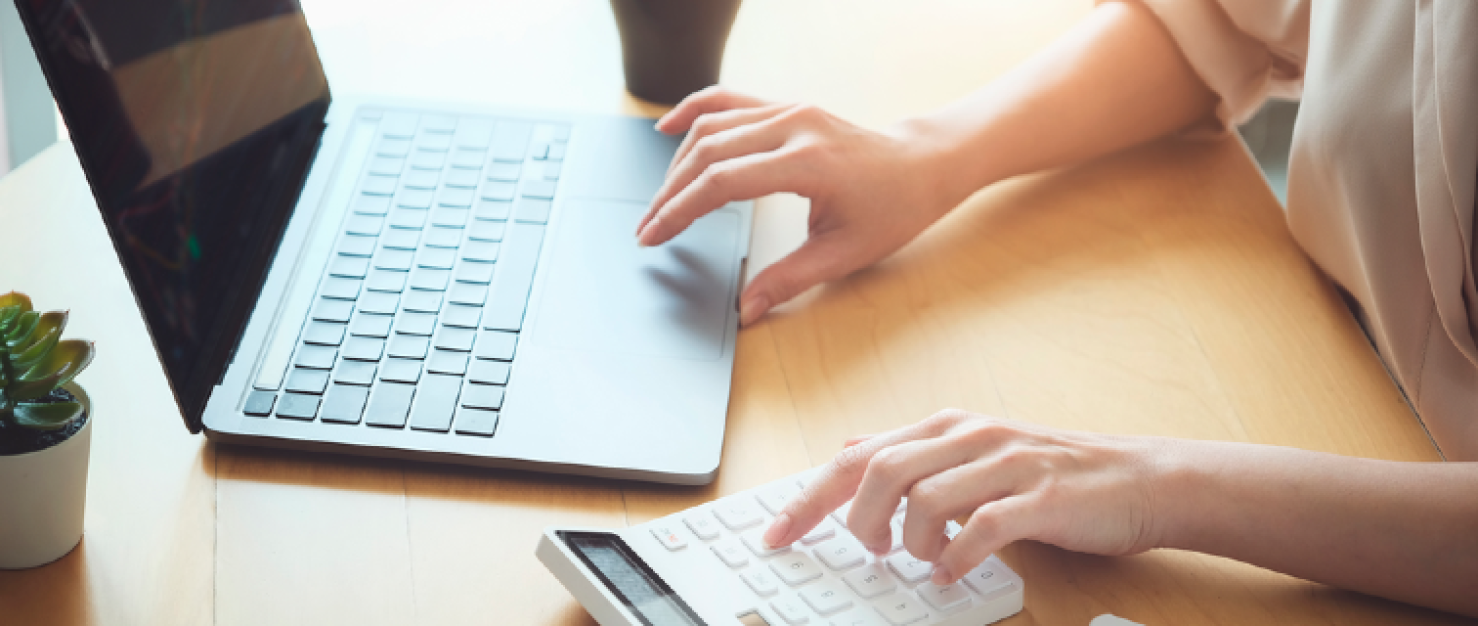 Vrouw werkt aan bureau op laptop en rekenmachine